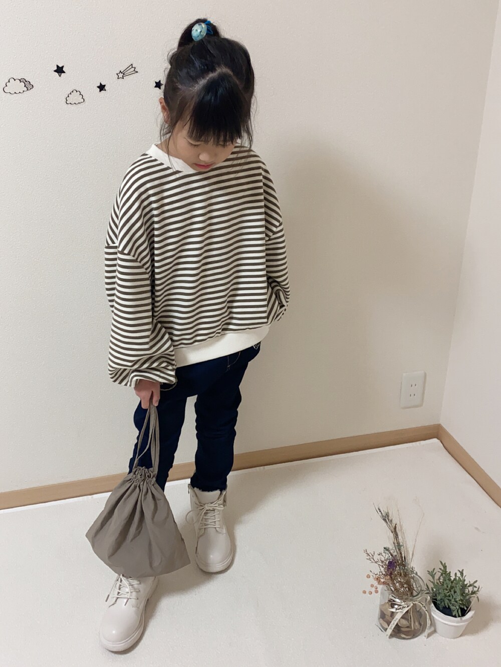 ブルー系のデニムパンツ、ブラウン系のバッグ、ホワイト系のブーツを着用したキッズの秋コーディネートの2枚目の写真