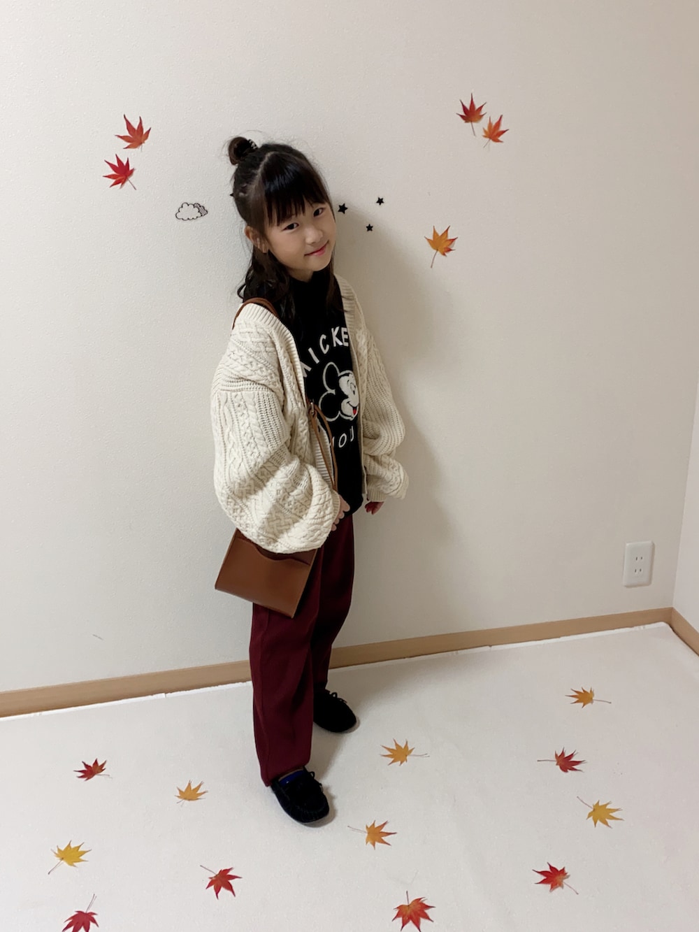 レッド系のその他パンツ、ホワイト系のカーディガン/ボレロ、ブラウン系のショルダーバッグを着用したキッズの秋コーディネートの3枚目の写真