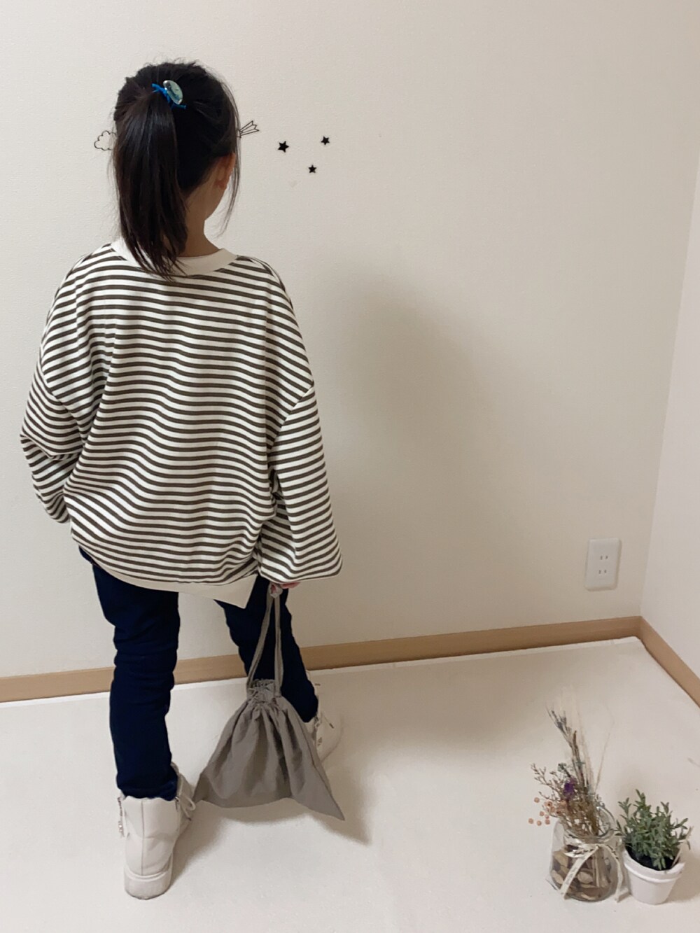 ブルー系のデニムパンツ、ブラウン系のバッグ、ホワイト系のブーツを着用したキッズの秋コーディネートの3枚目の写真