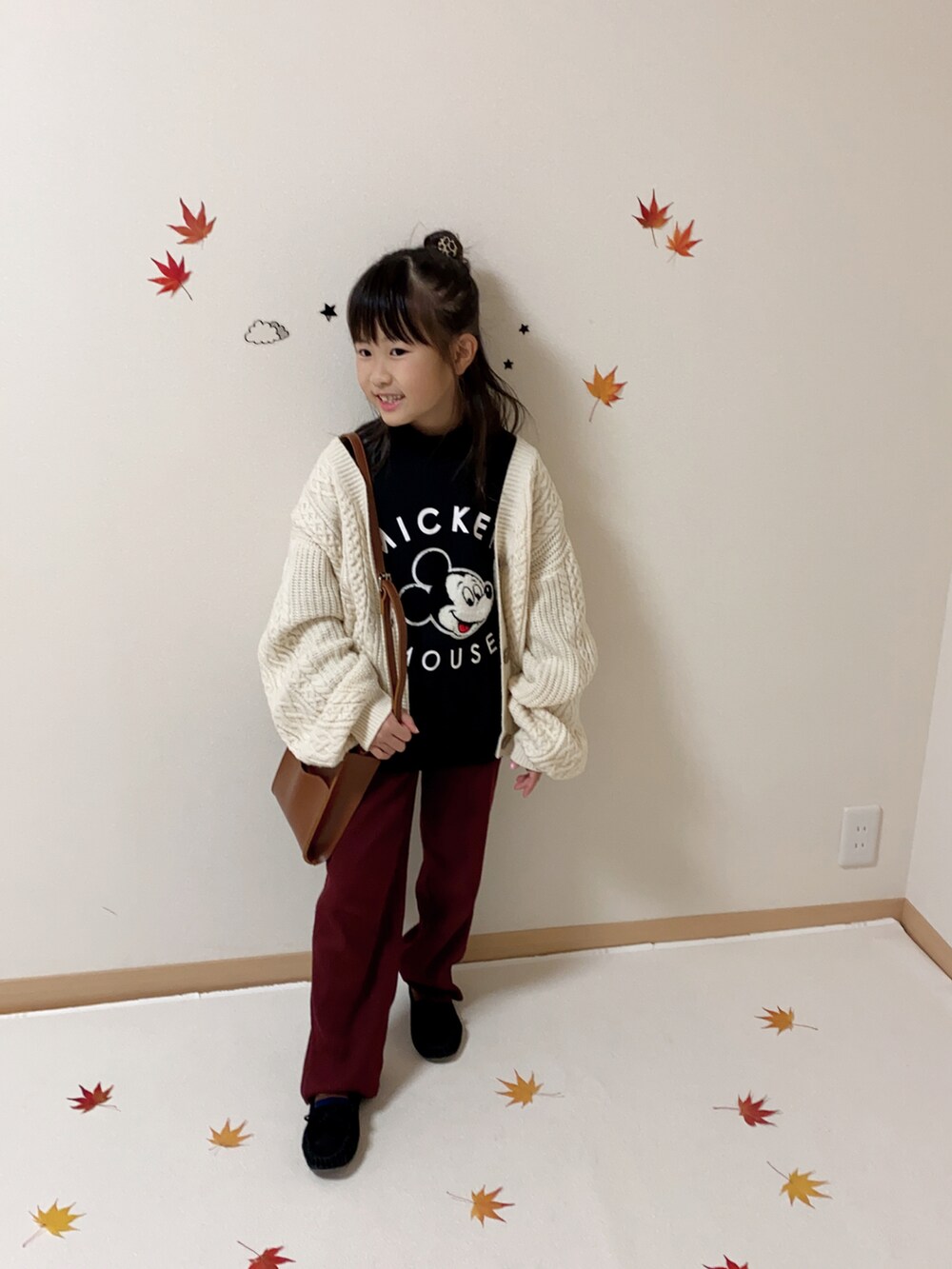 レッド系のその他パンツ、ホワイト系のカーディガン/ボレロ、ブラウン系のショルダーバッグを着用したキッズの秋コーディネートの2枚目の写真