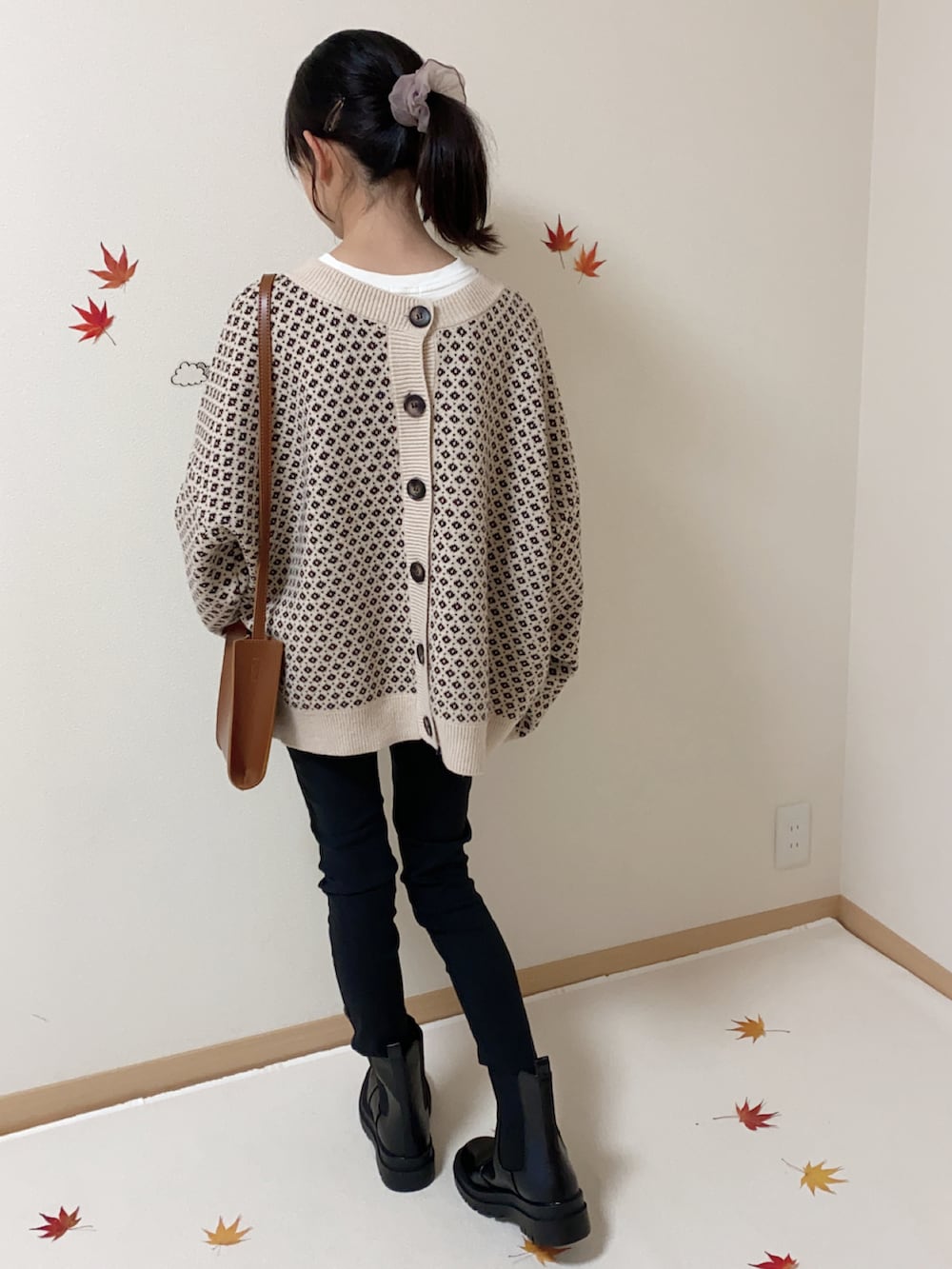 ブラック系のパンツ、ブラック系のブーツ、ブラウン系のショルダーバッグを着用したキッズの秋コーディネートの2枚目の写真