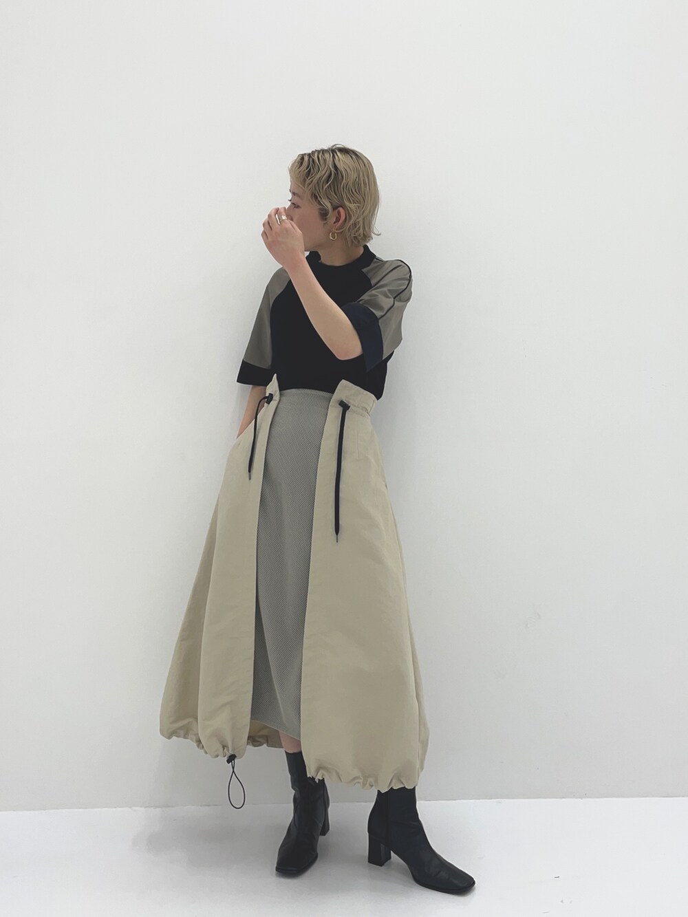 ベージュ系のスカート、ブラック系のTシャツ/カットソーを着用したレディースの春コーディネートの2枚目の写真