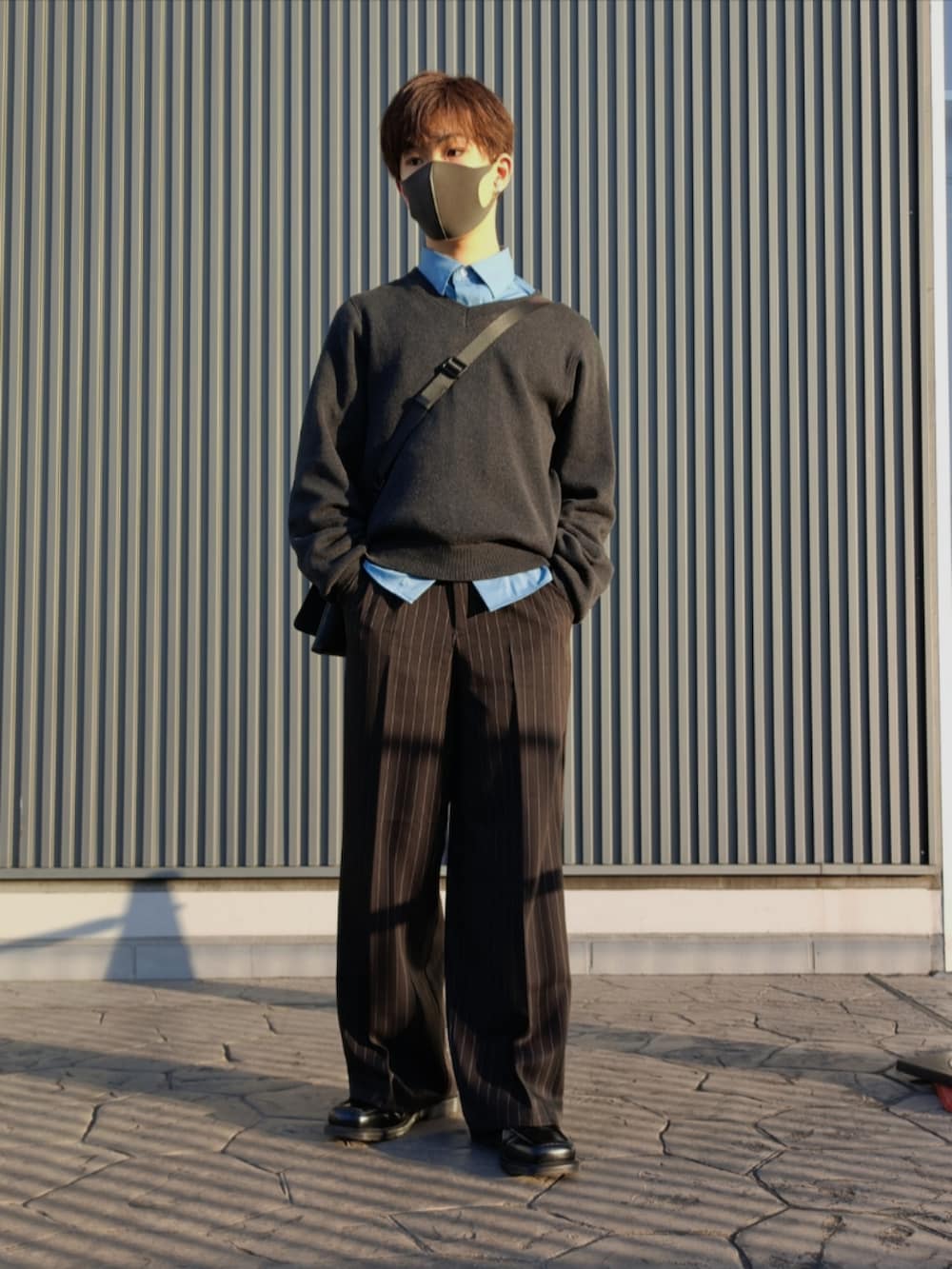 ブルー系のシャツ/ブラウス、ブラック系のニット/セーター、ブラック系のクラッチバッグを着用したメンズの冬コーディネートの2枚目の写真