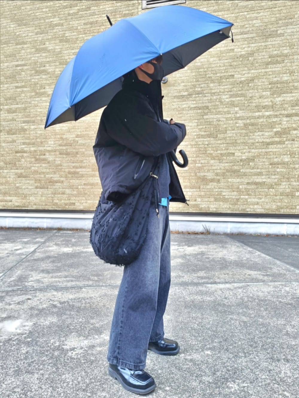 ブラック系のダウンジャケット/コート、ブラック系のニット/セーター、ブルー系のシャツ/ブラウスを着用したメンズの冬コーディネートの3枚目の写真