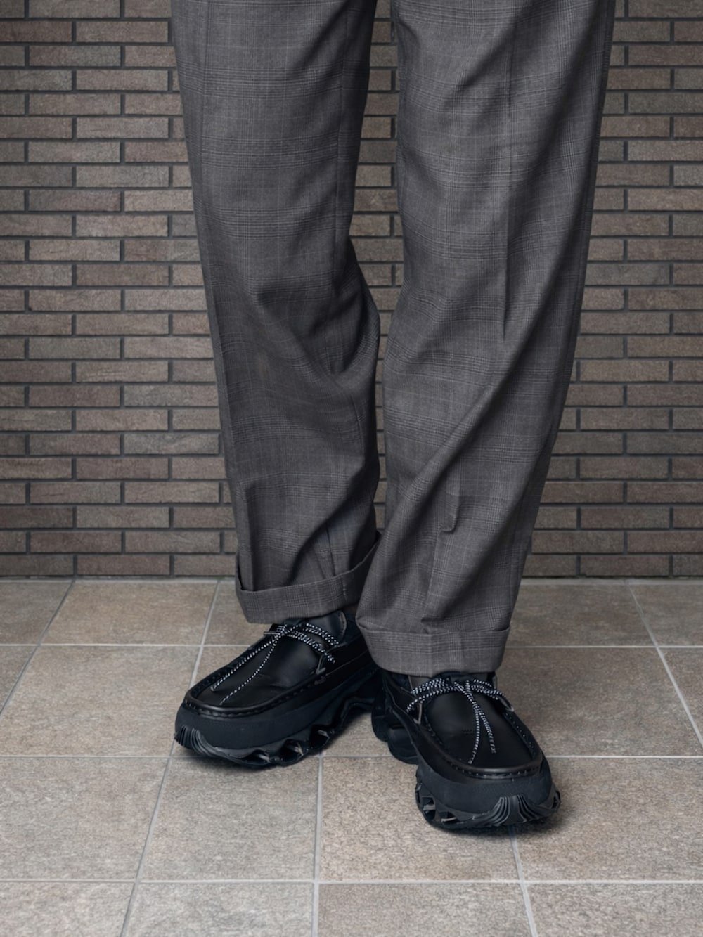 ブラック系のパーカー、ブラック系のその他アウター、グレー系のスラックスを着用したメンズの冬コーディネートの3枚目の写真