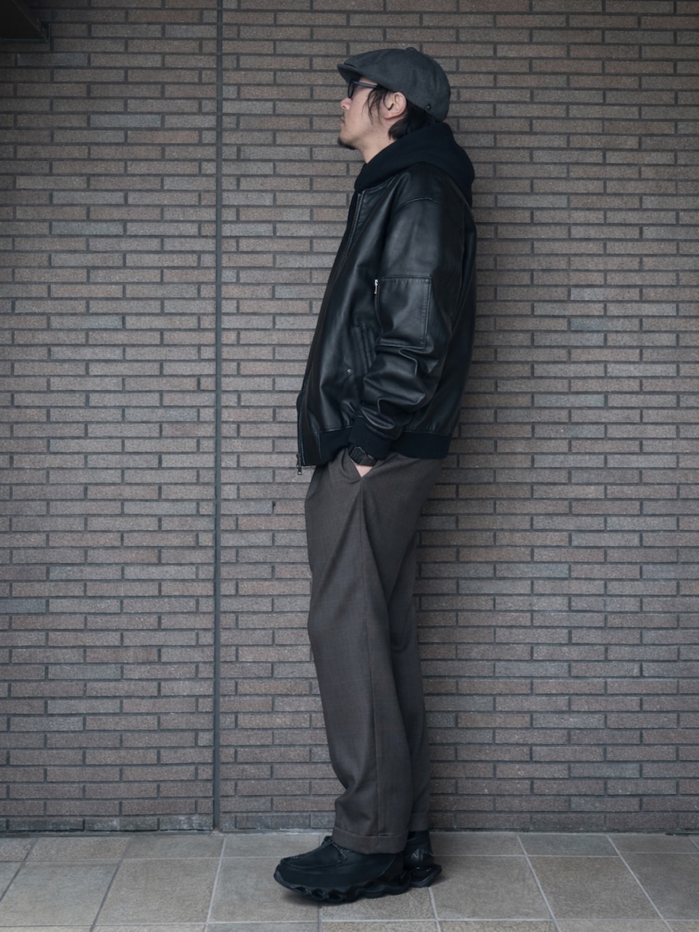 ブラック系のパーカー、ブラック系のその他アウター、グレー系のスラックスを着用したメンズの冬コーディネートの2枚目の写真