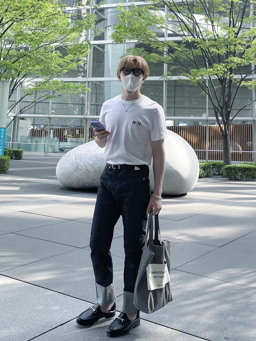 ホワイト系のTシャツ/カットソー、ブルー系のデニムパンツ、グレー系のトートバッグを着用したメンズの春コーディネートの2枚目の写真