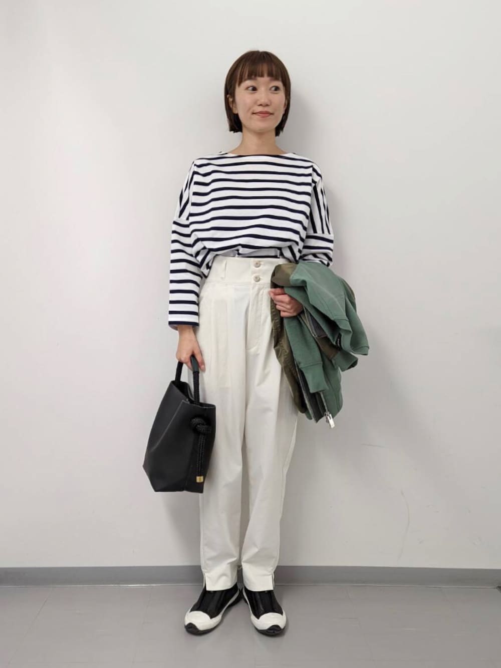 グリーン系のブルゾン、ブラック系のハンドバッグ、その他のTシャツ/カットソーを着用したレディースの冬コーディネートの2枚目の写真