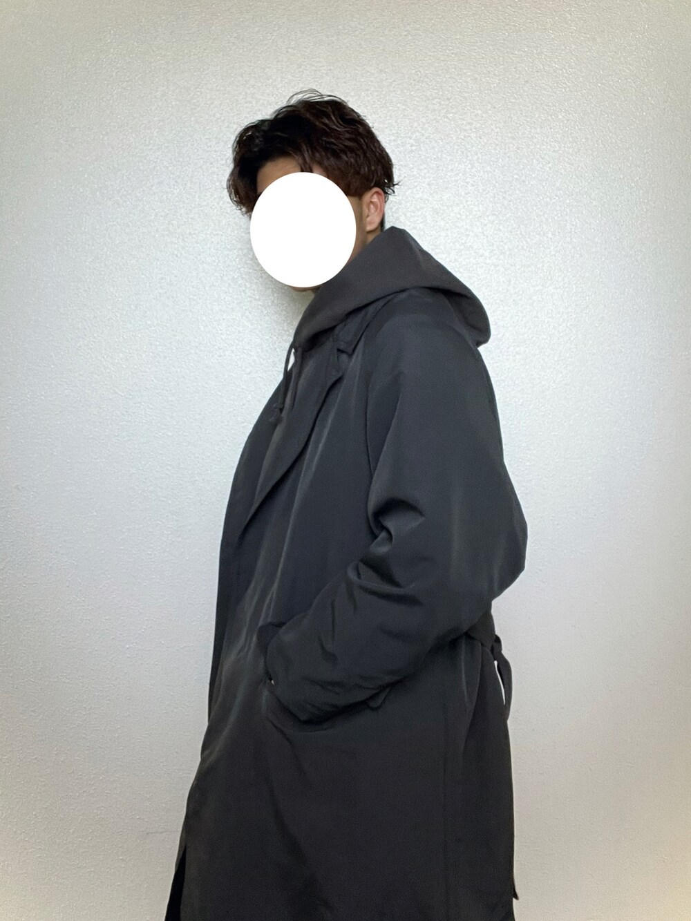 グレー系のチェスターコート、グレー系のパーカー、ホワイト系のスラックスを着用したメンズの冬コーディネートの3枚目の写真