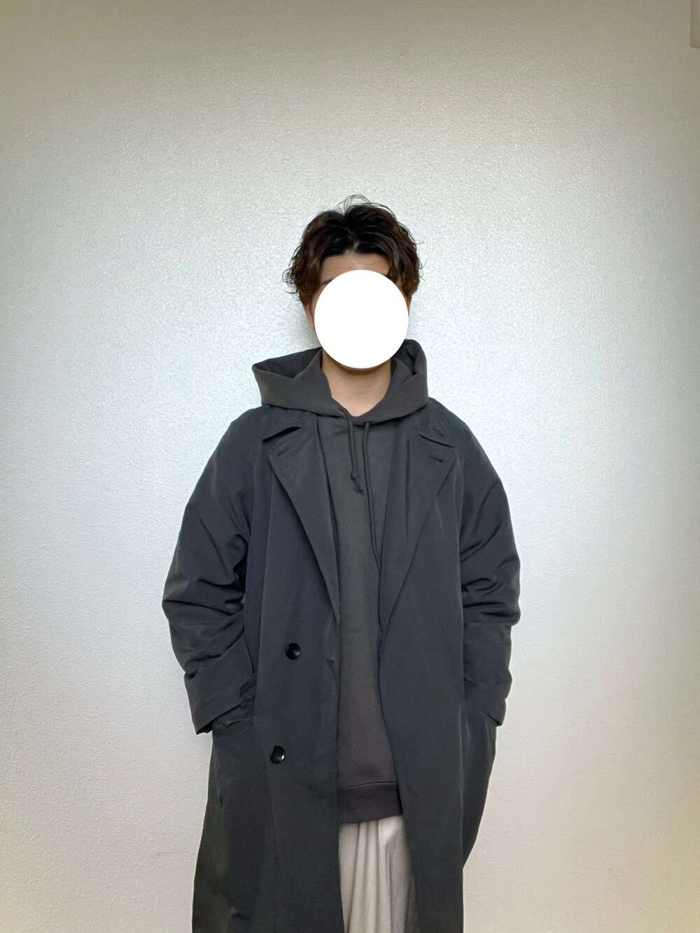 グレー系のチェスターコート、グレー系のパーカー、ホワイト系のスラックスを着用したメンズの冬コーディネートの2枚目の写真