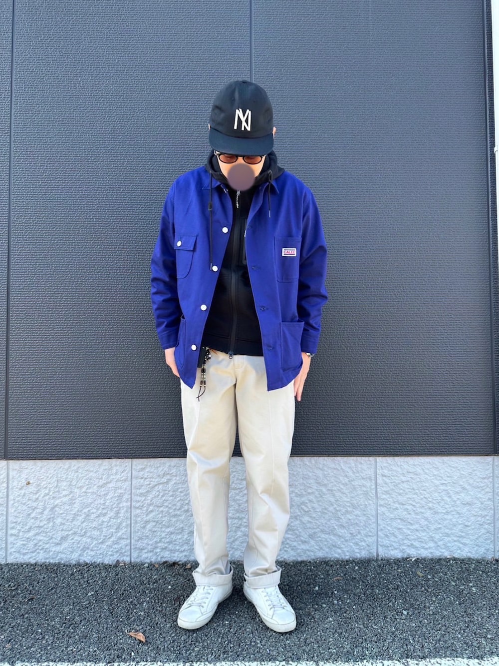 ブルー系のカバーオール、ブラック系のパーカー、ベージュ系のチノパンツを着用したメンズの冬コーディネートの3枚目の写真