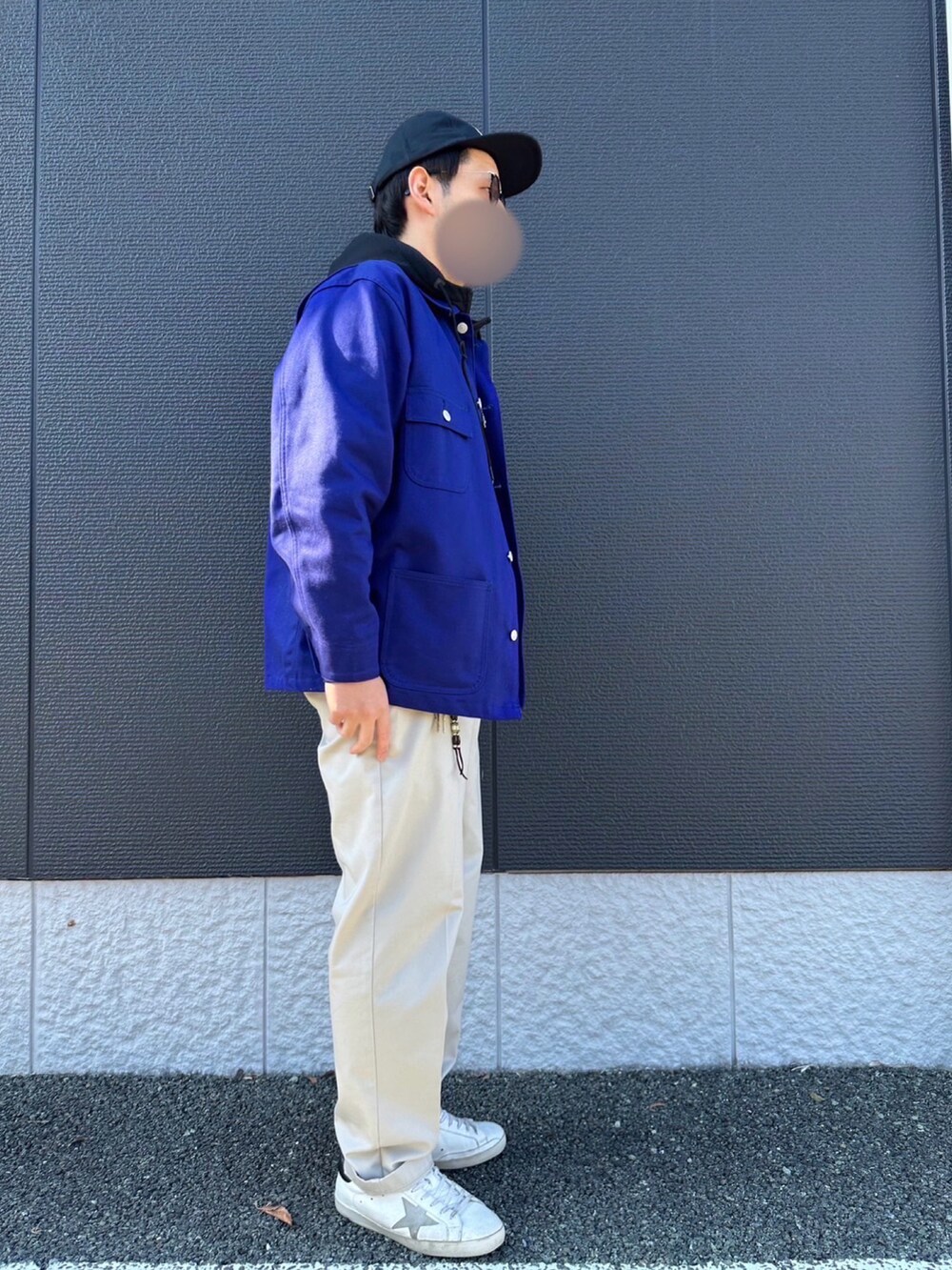 ブルー系のカバーオール、ブラック系のパーカー、ベージュ系のチノパンツを着用したメンズの冬コーディネートの2枚目の写真