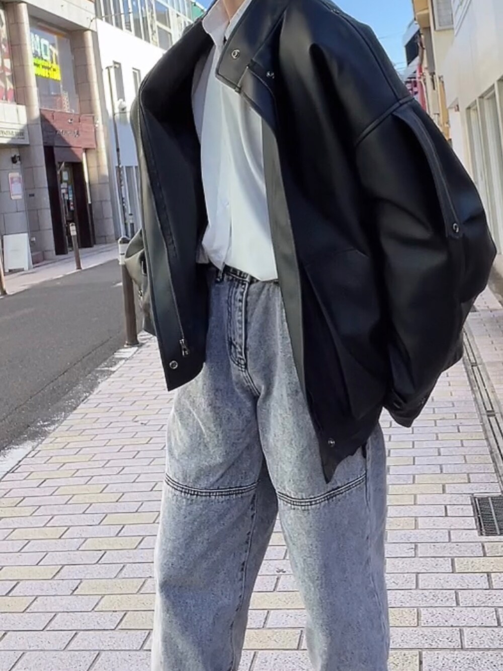 ブラック系のライダースジャケット、グレー系のデニムパンツ、ブラック系のローファーを着用したメンズの冬コーディネートの2枚目の写真