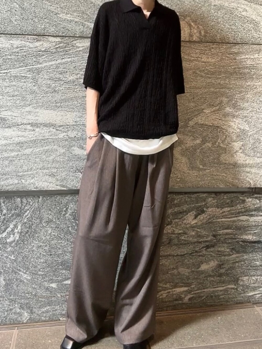 ブラック系のポロシャツ、ベージュ系のその他パンツ、ブラック系のブーツを着用したメンズの春コーディネートの2枚目の写真