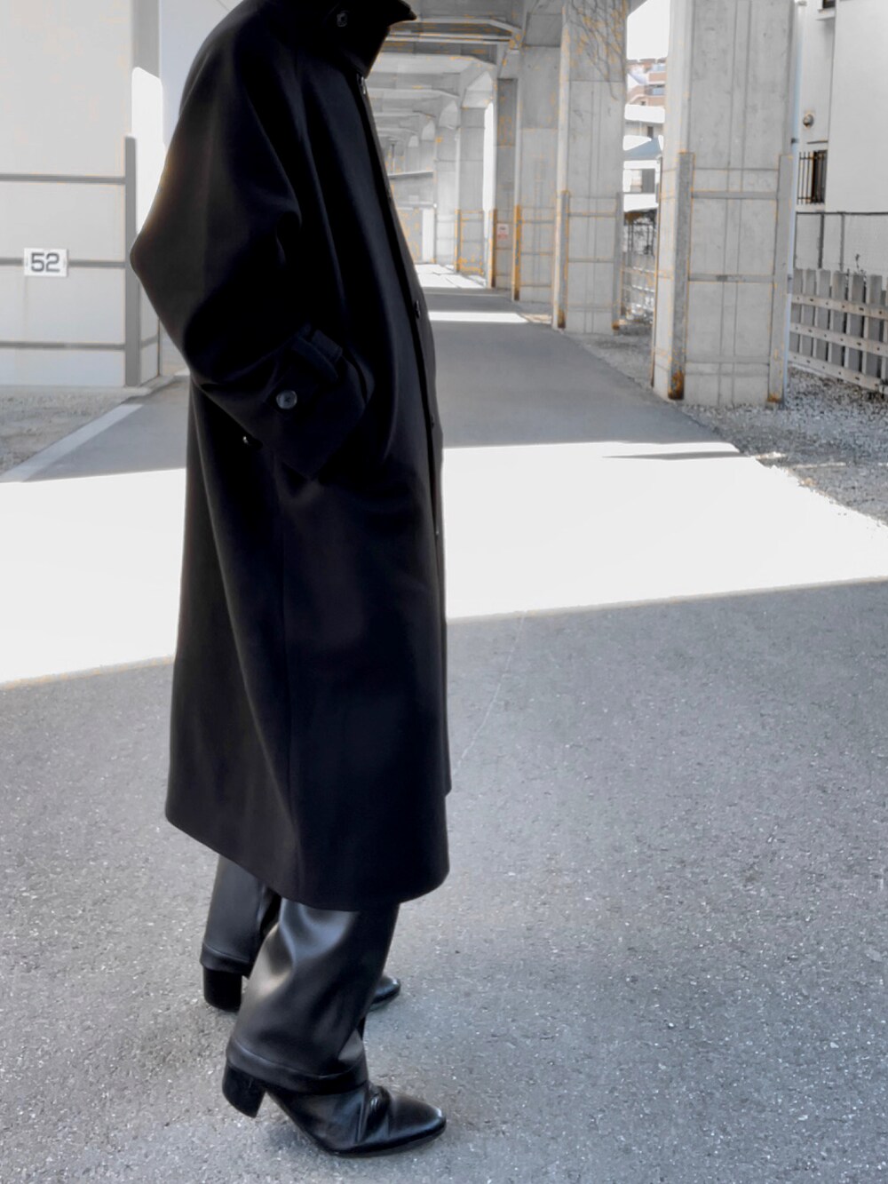 ブラック系のその他パンツ、ブラック系のブーツ、ブラック系のステンカラーコートを着用したメンズの冬コーディネートの3枚目の写真