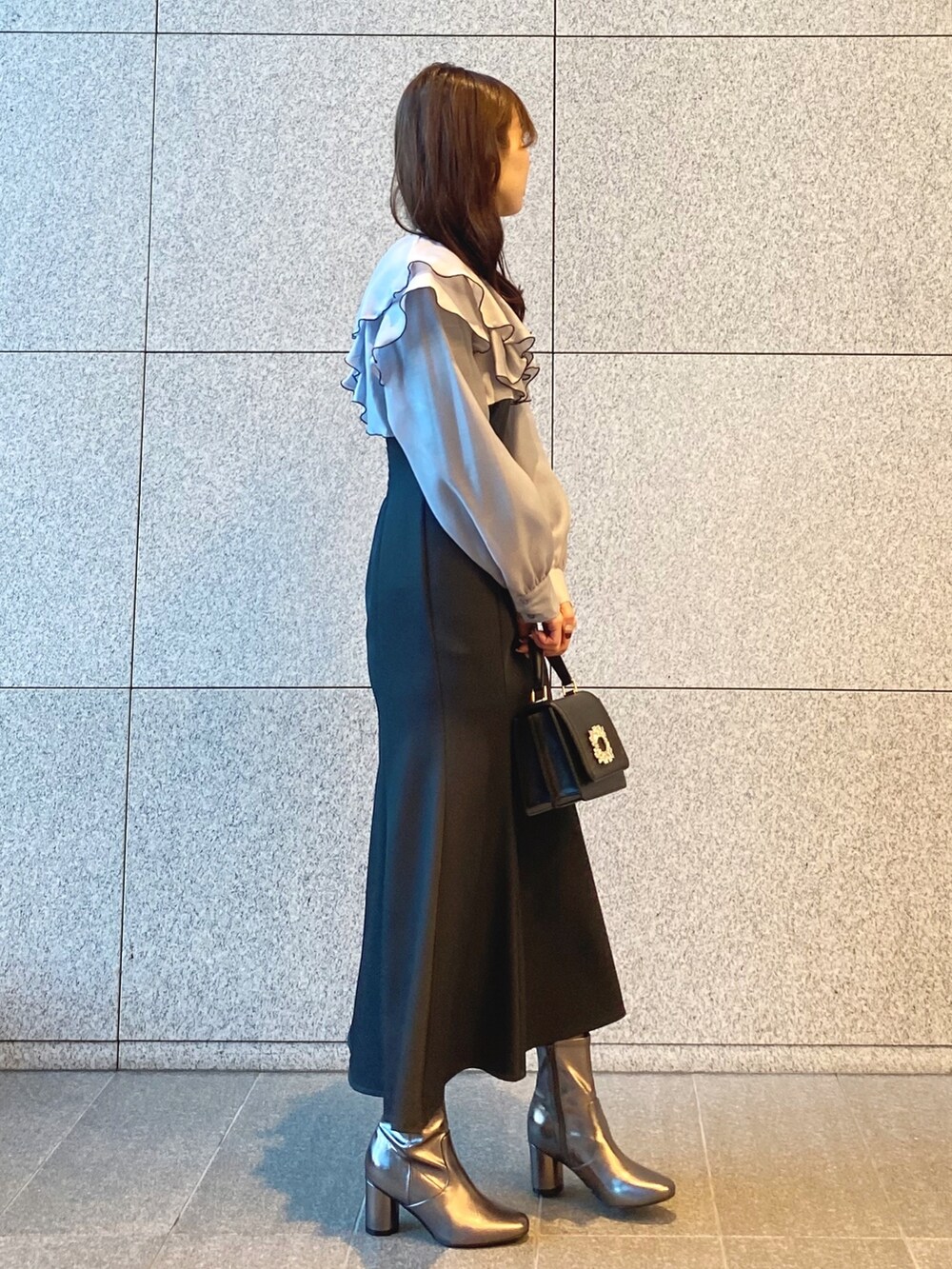 ブラック系のショルダーバッグ、グレー系のワンピース、ゴールド系のブーツを着用したレディースの冬コーディネートの3枚目の写真