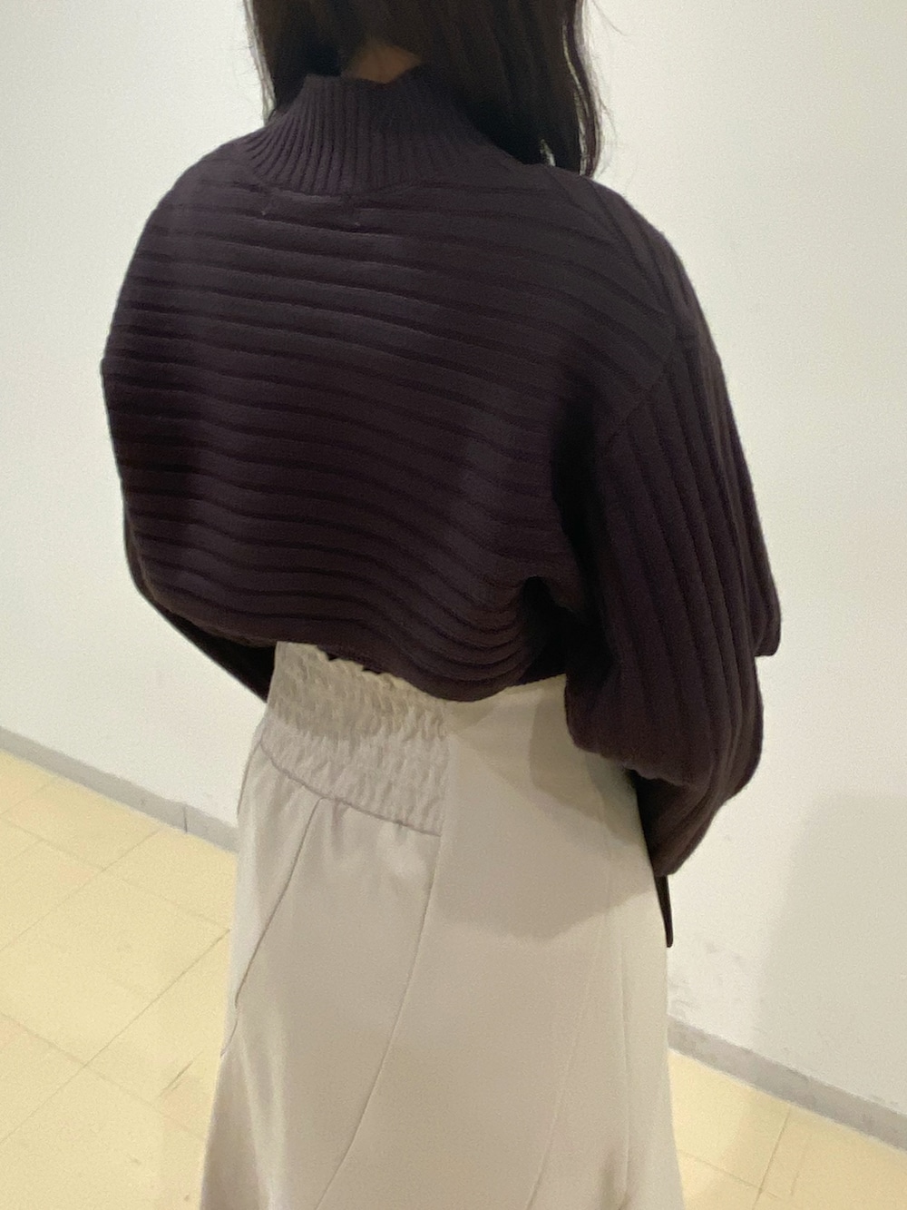 ブラウン系のニット/セーター、ベージュ系のスカート、ブラック系のハンドバッグを着用したレディースの秋コーディネートの6枚目の写真