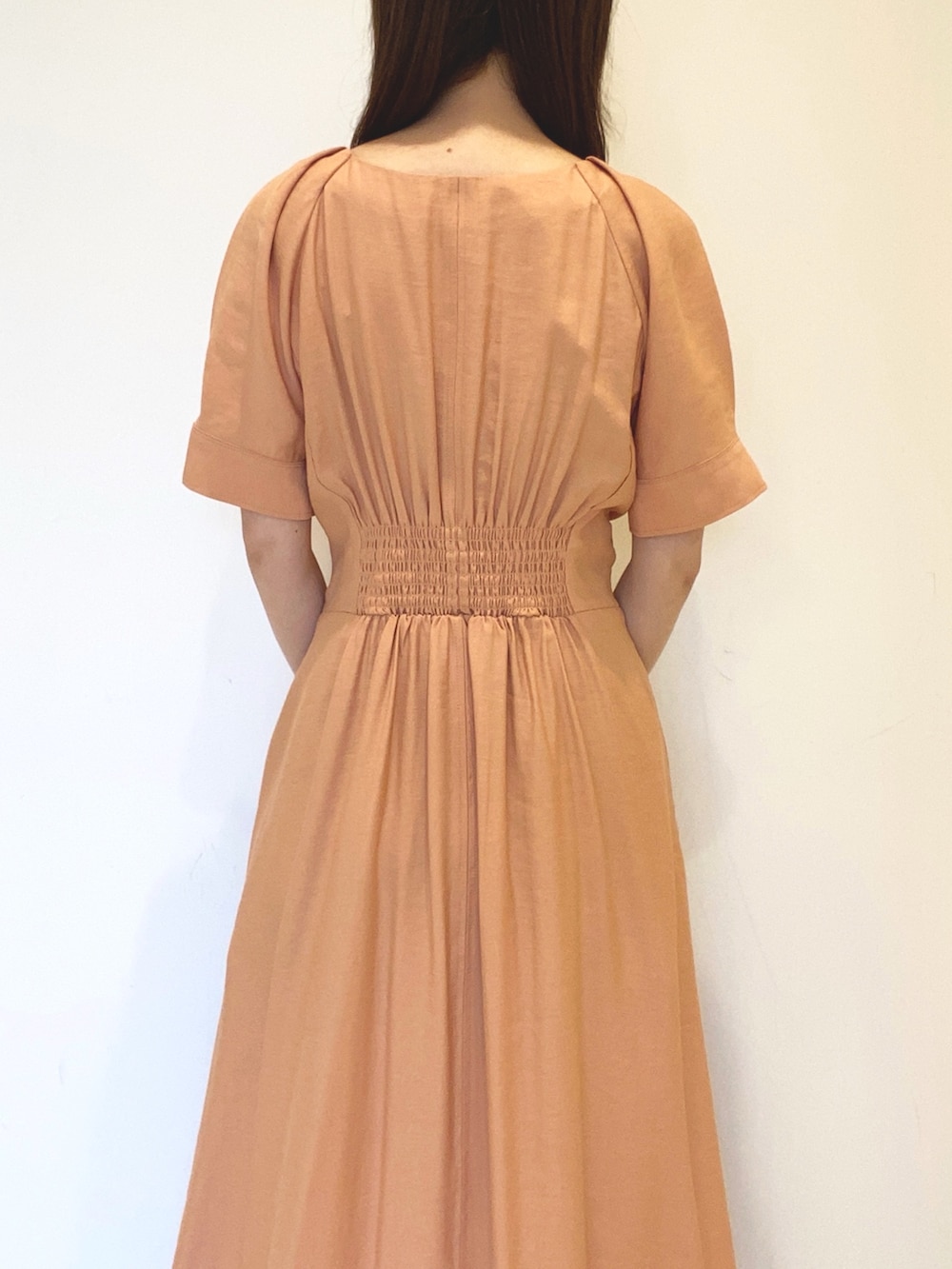 オレンジ系のワンピース、ブラック系のハンドバッグ、ホワイト系のサンダルを着用したレディースの春コーディネートの6枚目の写真