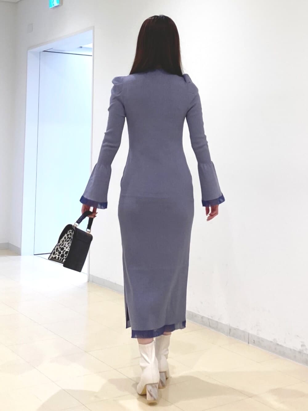 ホワイト系のブーツ、ブルー系のワンピース、ブラック系のハンドバッグを着用したレディースの冬コーディネートの3枚目の写真