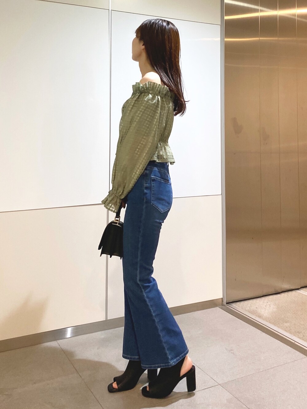 グリーン系のシャツ/ブラウス、ブルー系のデニムパンツ、ブラック系のショルダーバッグを着用したレディースの冬コーディネートの2枚目の写真