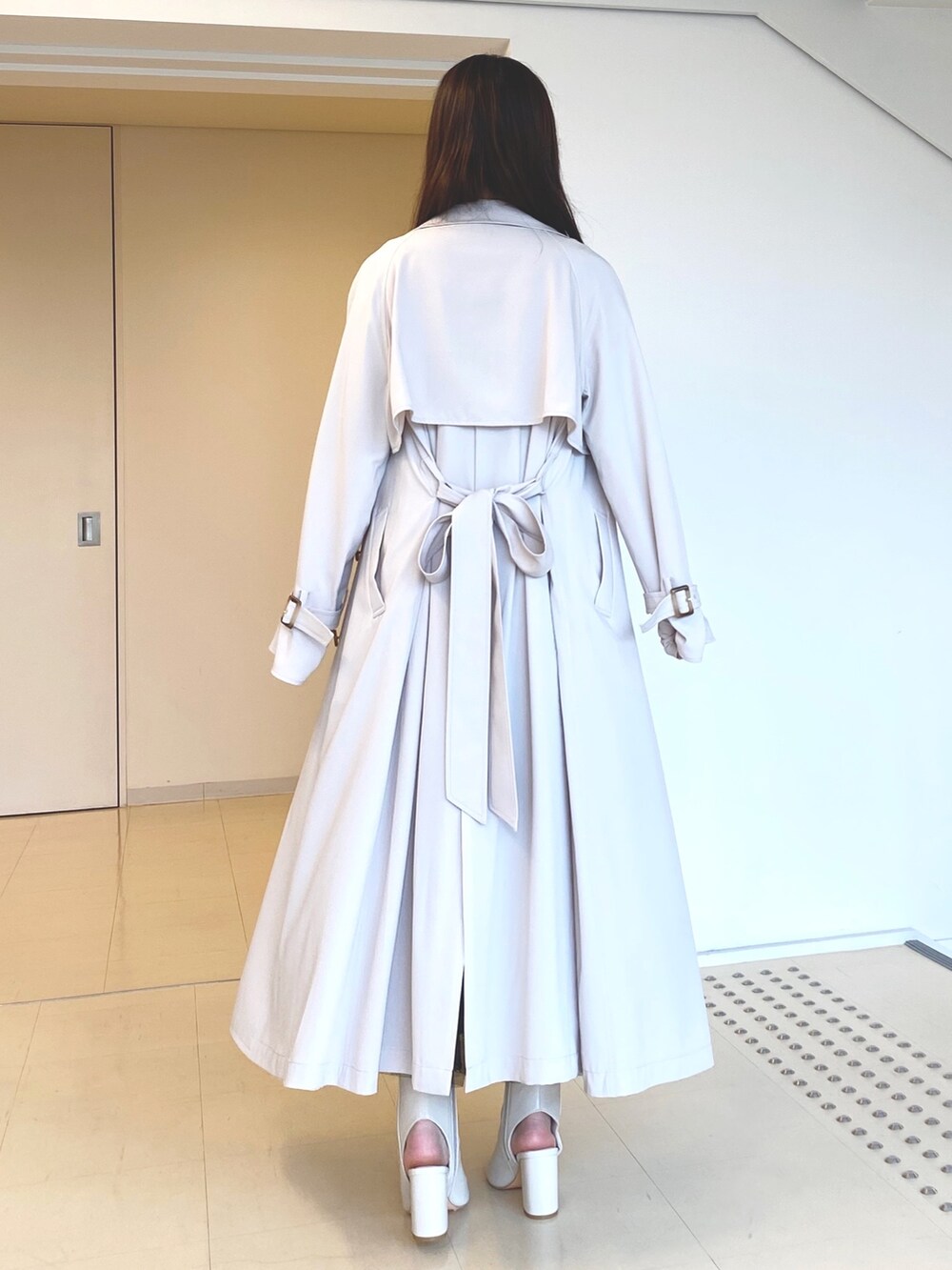 ブラック系のワンピース、ホワイト系のブーツ、ピンク系のトレンチコートを着用したレディースの春コーディネートの5枚目の写真