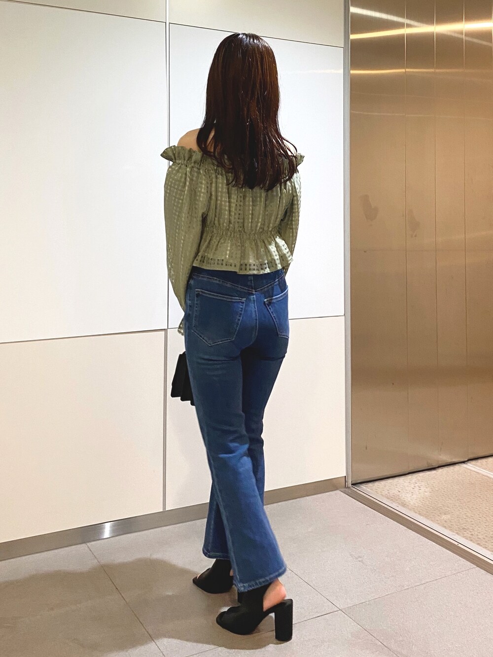 グリーン系のシャツ/ブラウス、ブルー系のデニムパンツ、ブラック系のショルダーバッグを着用したレディースの冬コーディネートの3枚目の写真