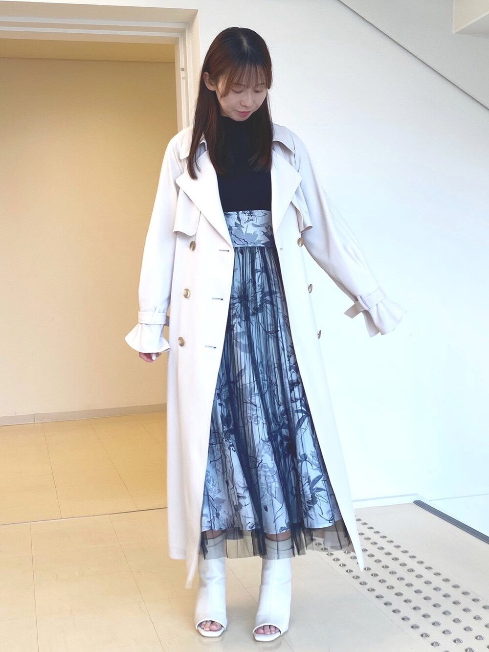 ブラック系のワンピース、ホワイト系のブーツ、ピンク系のトレンチコートを着用したレディースの春コーディネートの2枚目の写真