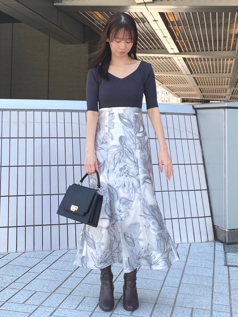 ホワイト系のトレンチコート、グレー系のワンピース、ブラック系のハンドバッグを着用したレディースの春コーディネートの5枚目の写真