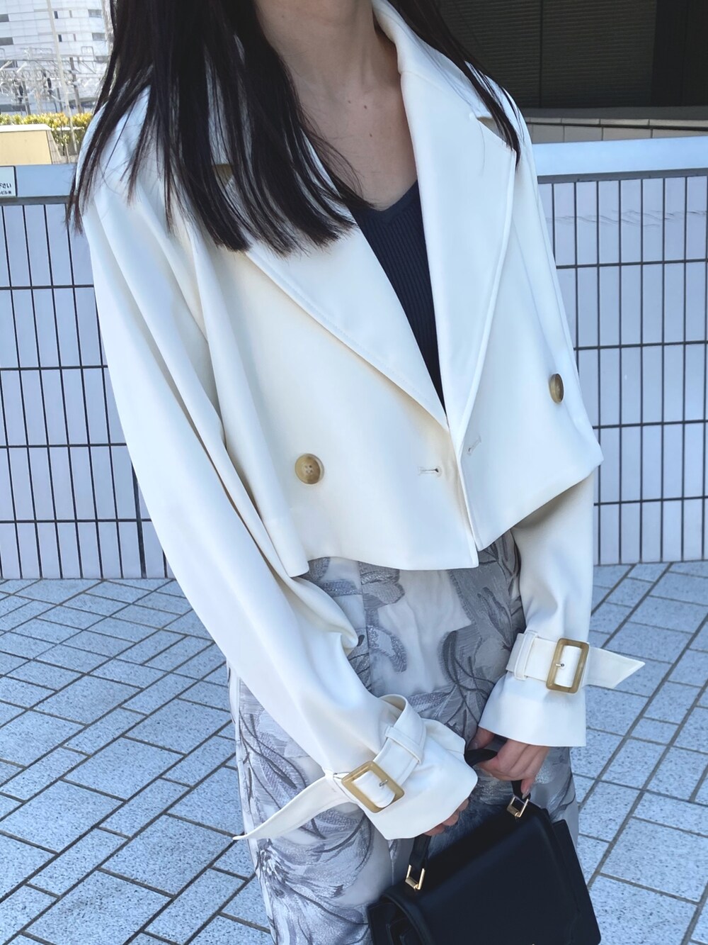 ホワイト系のトレンチコート、グレー系のワンピース、ブラック系のハンドバッグを着用したレディースの春コーディネートの6枚目の写真