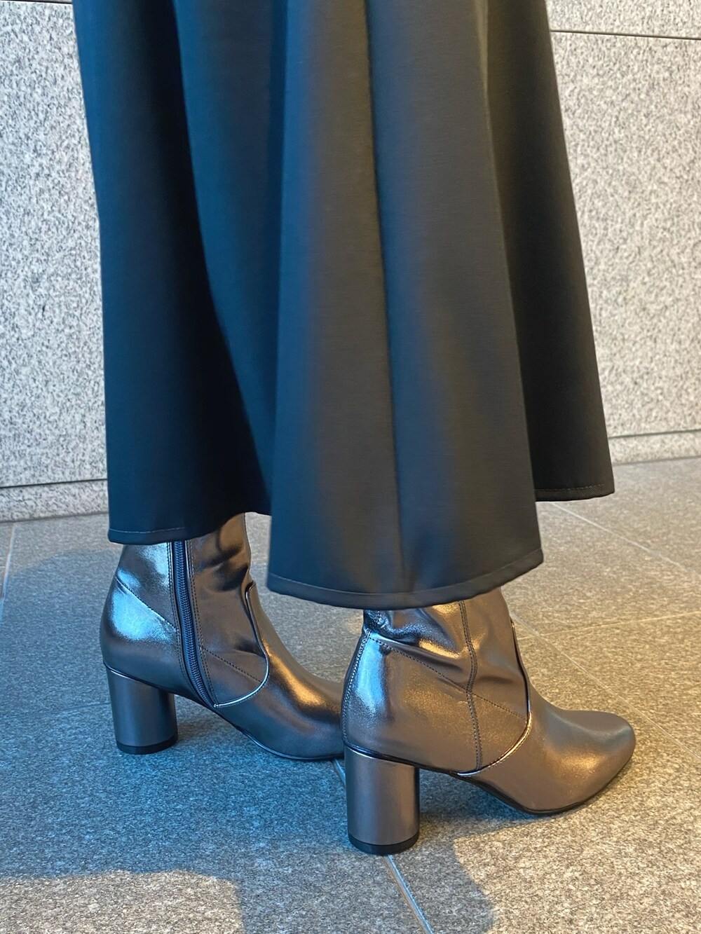 ブラック系のショルダーバッグ、グレー系のワンピース、ゴールド系のブーツを着用したレディースの冬コーディネートの7枚目の写真