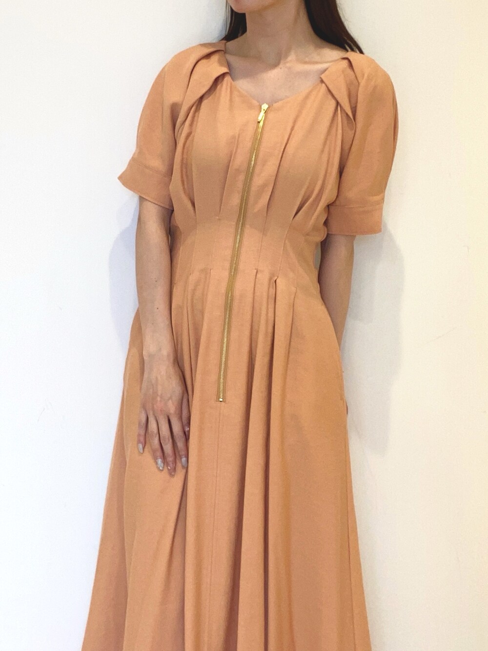 オレンジ系のワンピース、ブラック系のハンドバッグ、ホワイト系のサンダルを着用したレディースの春コーディネートの5枚目の写真