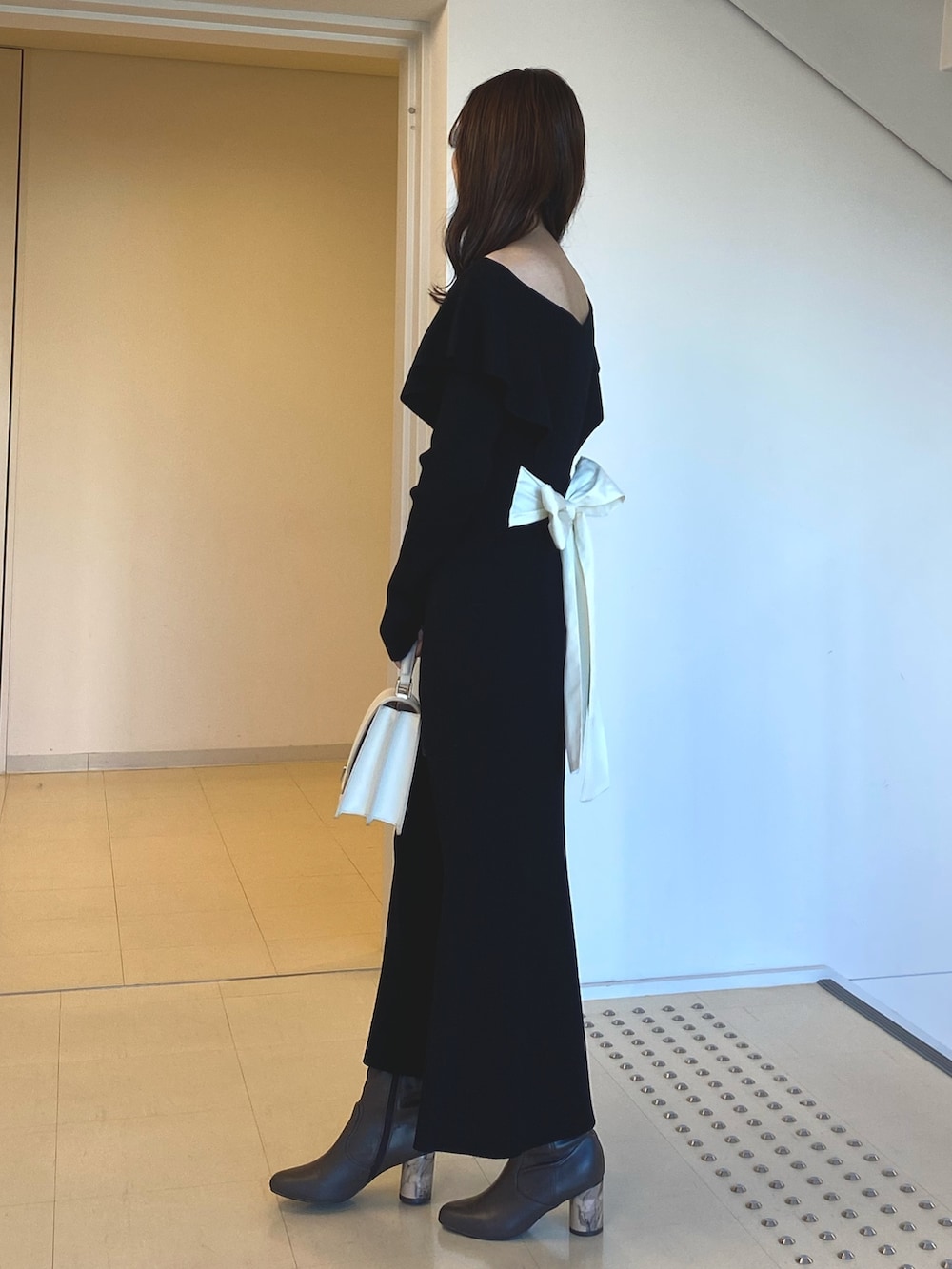 ブラック系のワンピース、ホワイト系のハンドバッグ、ブラウン系のブーツを着用したレディースの冬コーディネートの3枚目の写真