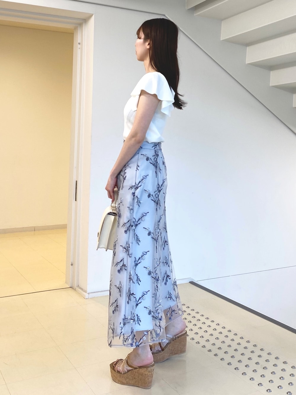 ホワイト系のニット/セーター、ブルー系のスカート、ホワイト系のハンドバッグを着用したレディースの春コーディネートの2枚目の写真