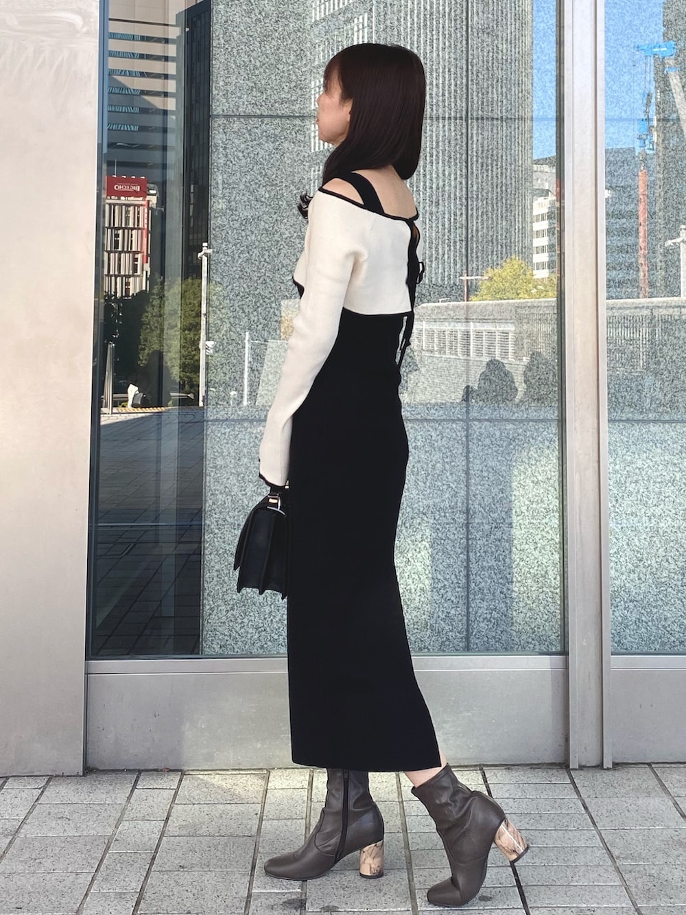 ブラック系のワンピース、ブラック系のショルダーバッグ、ブラウン系のブーツを着用したレディースの冬コーディネートの3枚目の写真