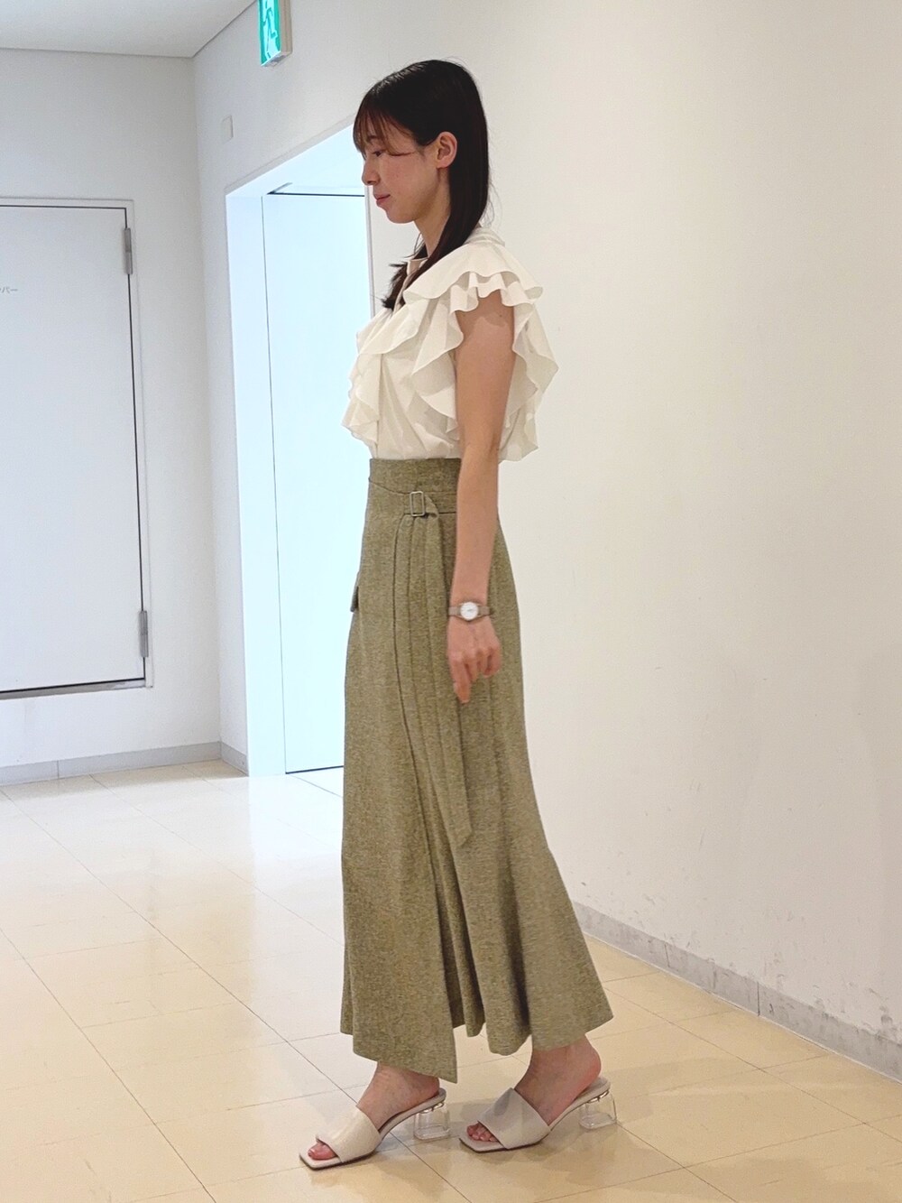 ホワイト系のシャツ/ブラウス、グリーン系のスカート、ブラウン系のハンドバッグを着用したレディースの春コーディネートの2枚目の写真