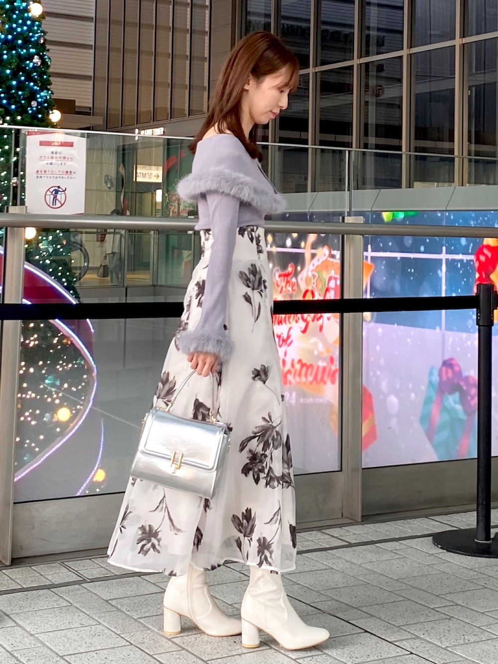 グレー系のニット/セーター、ホワイト系のスカート、シルバー系のハンドバッグを着用したレディースの冬コーディネートの2枚目の写真