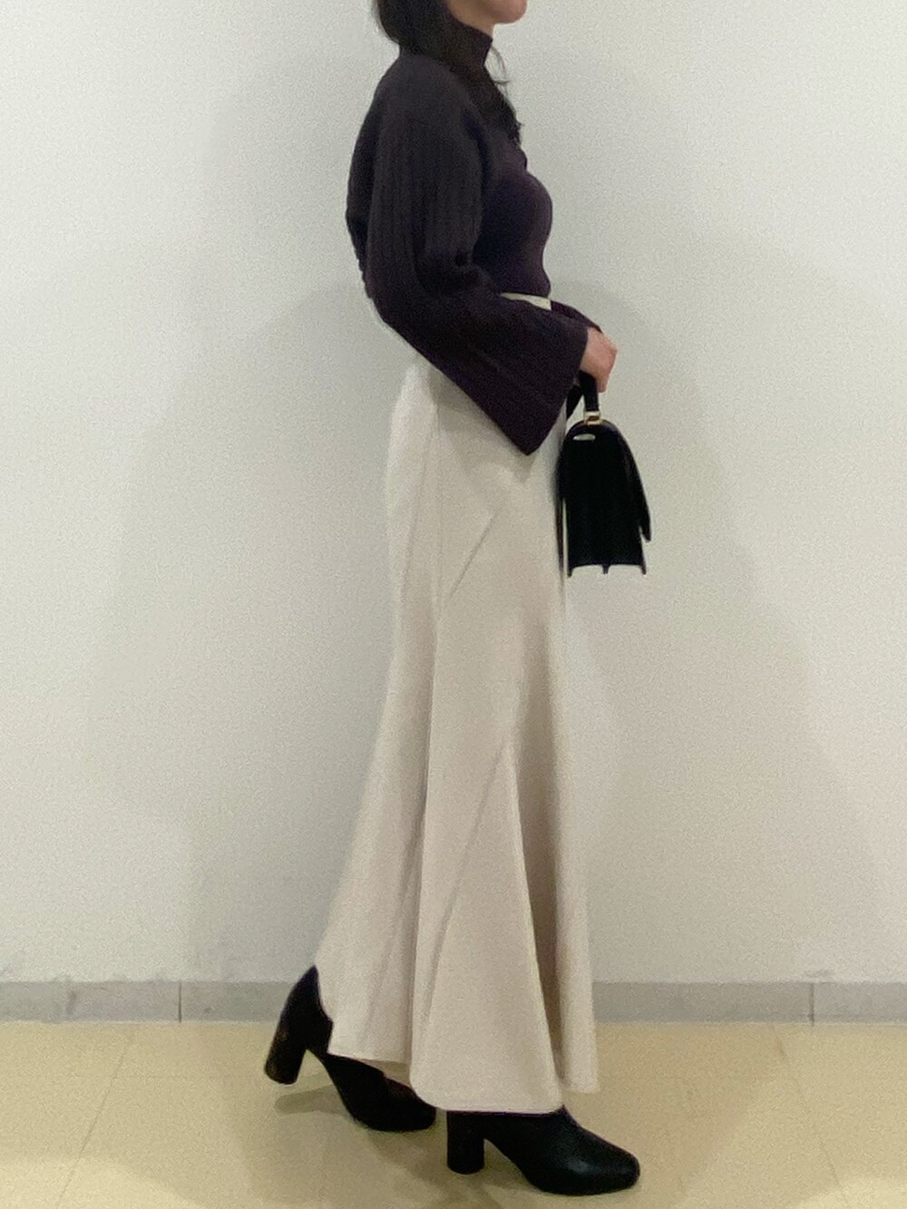 ブラウン系のニット/セーター、ベージュ系のスカート、ブラック系のハンドバッグを着用したレディースの秋コーディネートの3枚目の写真