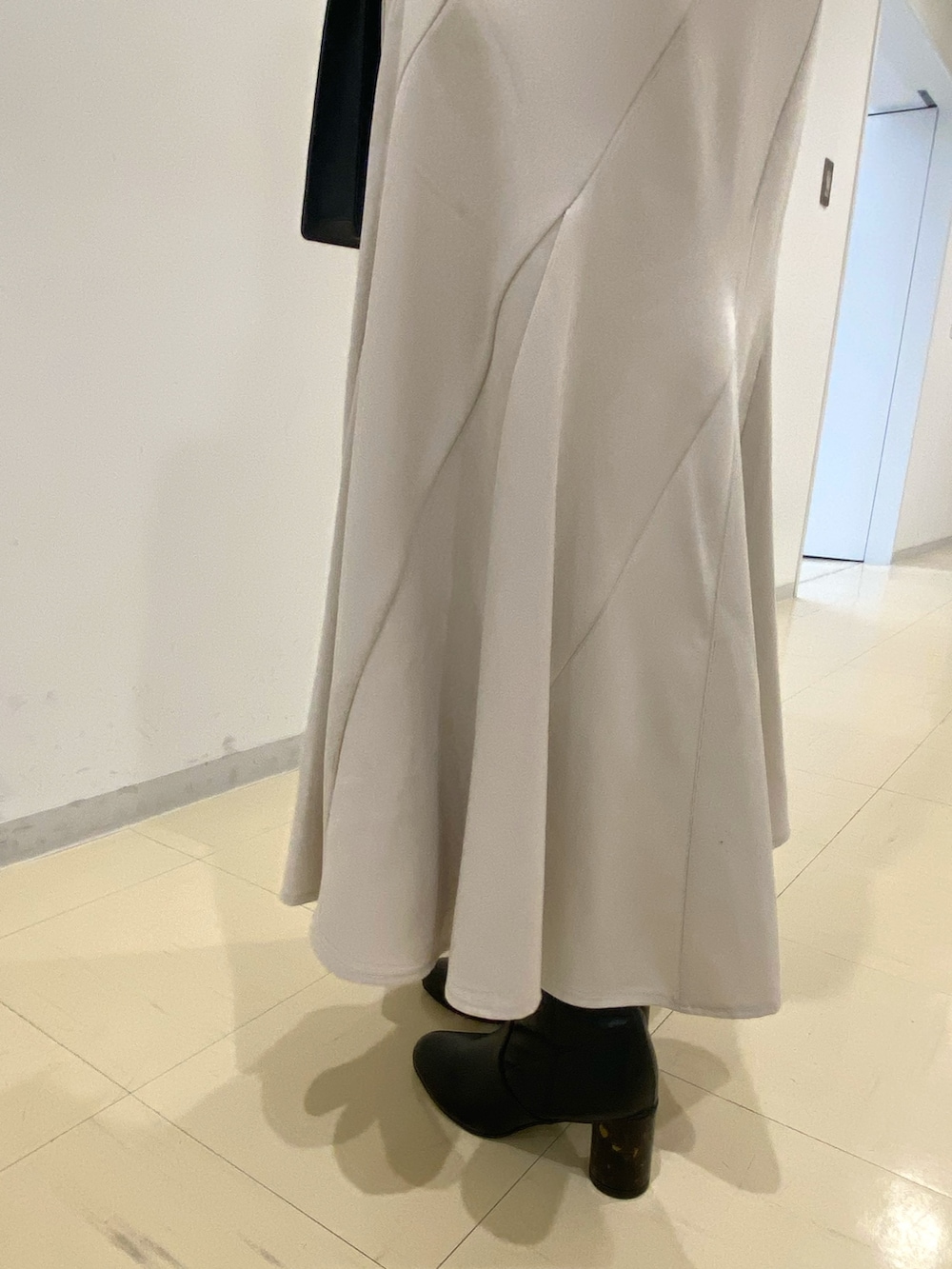 ブラウン系のニット/セーター、ベージュ系のスカート、ブラック系のハンドバッグを着用したレディースの秋コーディネートの7枚目の写真