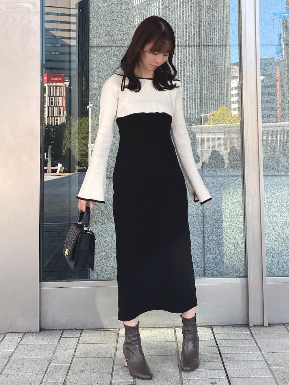 ブラック系のワンピース、ブラック系のショルダーバッグ、ブラウン系のブーツを着用したレディースの冬コーディネートの2枚目の写真