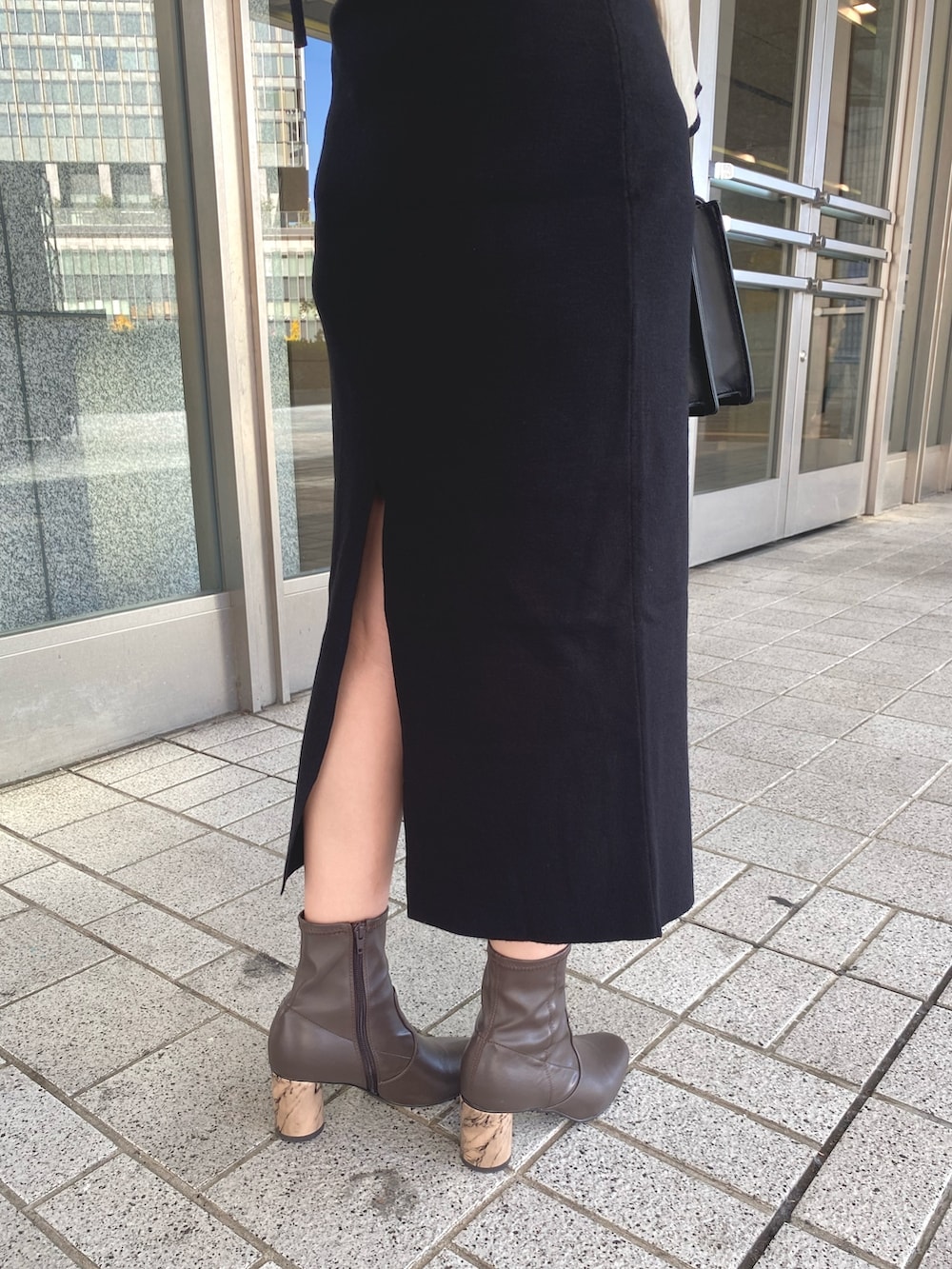 ブラック系のワンピース、ブラック系のショルダーバッグ、ブラウン系のブーツを着用したレディースの冬コーディネートの7枚目の写真