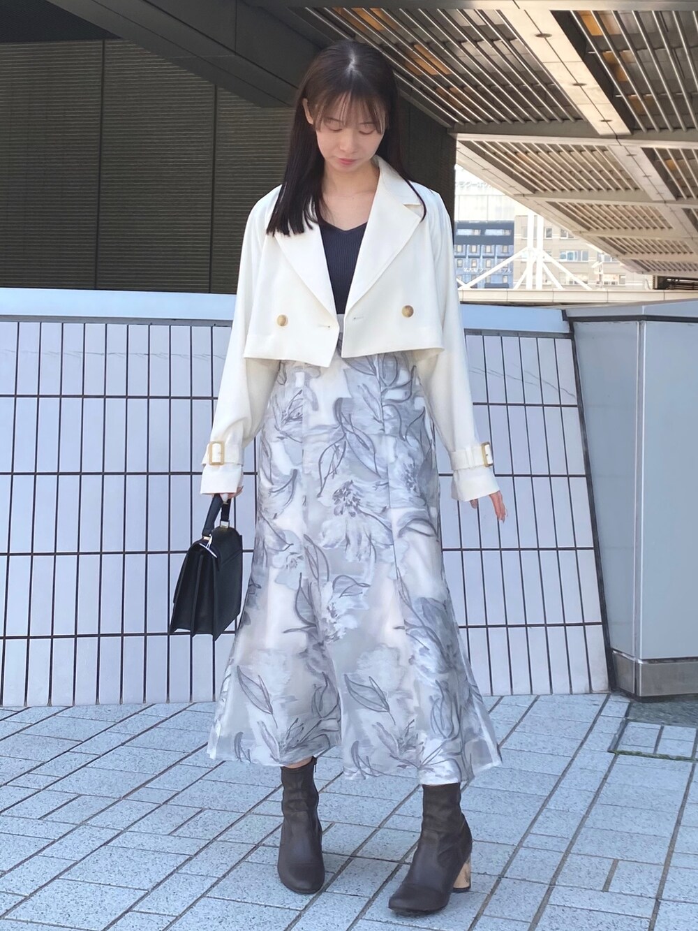 ホワイト系のトレンチコート、グレー系のワンピース、ブラック系のハンドバッグを着用したレディースの春コーディネートの4枚目の写真