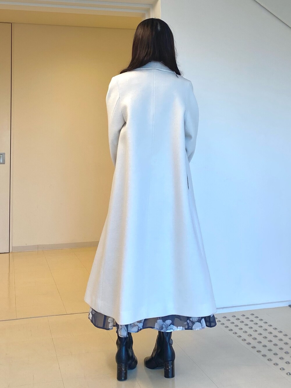 ホワイト系のチェスターコート、グレー系のワンピース、ブラック系のハンドバッグを着用したレディースの秋コーディネートの4枚目の写真