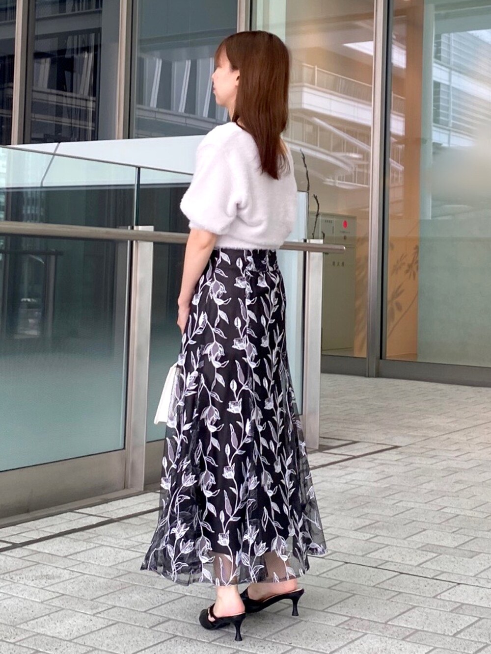 パープル系のカーディガン/ボレロ、グレー系のスカート、ホワイト系のハンドバッグを着用したレディースの夏コーディネートの2枚目の写真