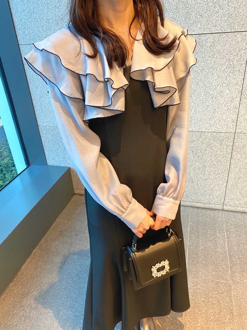 ブラック系のショルダーバッグ、グレー系のワンピース、ゴールド系のブーツを着用したレディースの冬コーディネートの5枚目の写真