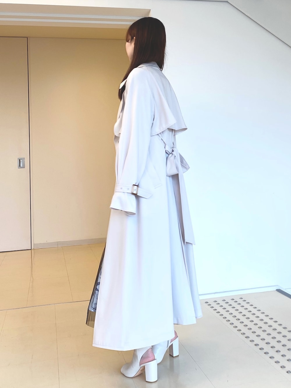 ブラック系のワンピース、ホワイト系のブーツ、ピンク系のトレンチコートを着用したレディースの春コーディネートの4枚目の写真
