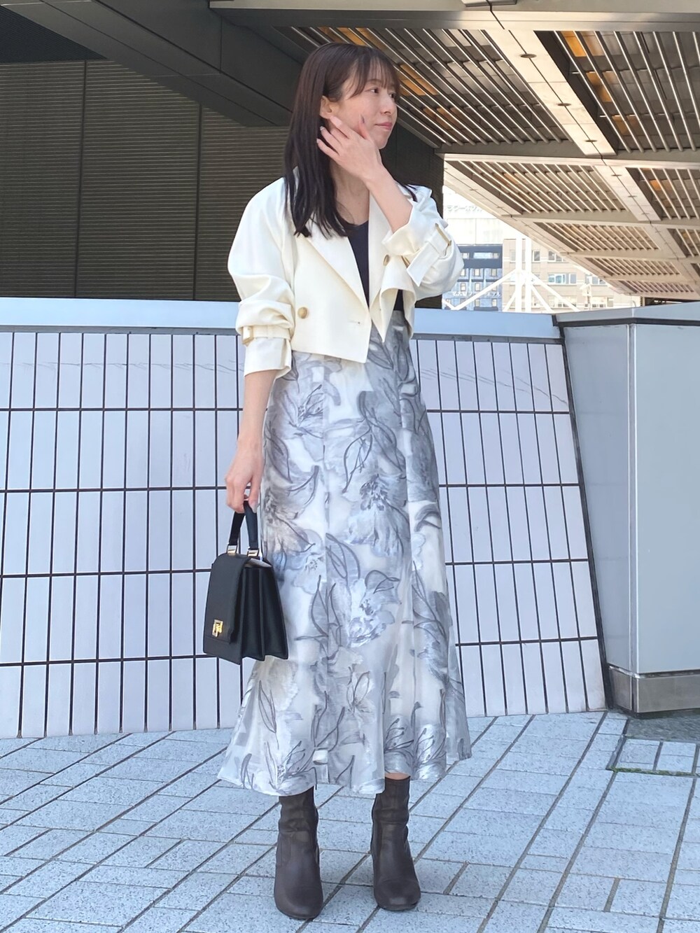 ホワイト系のトレンチコート、グレー系のワンピース、ブラック系のハンドバッグを着用したレディースの春コーディネートの2枚目の写真