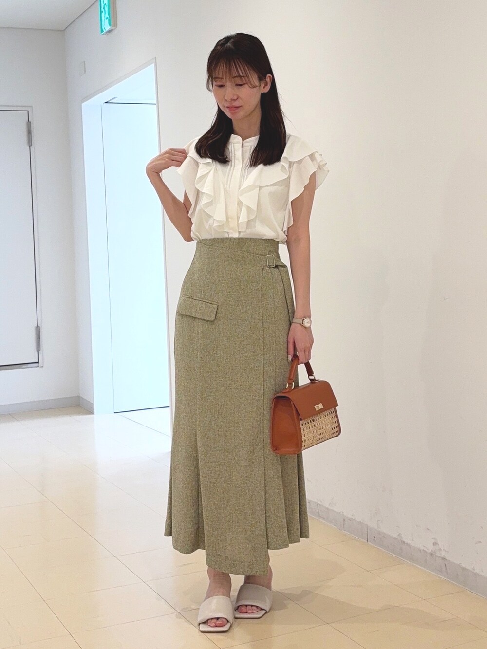 ホワイト系のシャツ/ブラウス、グリーン系のスカート、ブラウン系のハンドバッグを着用したレディースの春コーディネートの5枚目の写真