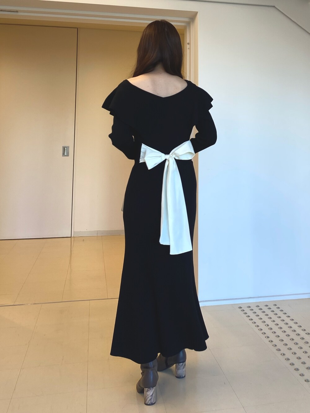 ブラック系のワンピース、ホワイト系のハンドバッグ、ブラウン系のブーツを着用したレディースの冬コーディネートの4枚目の写真