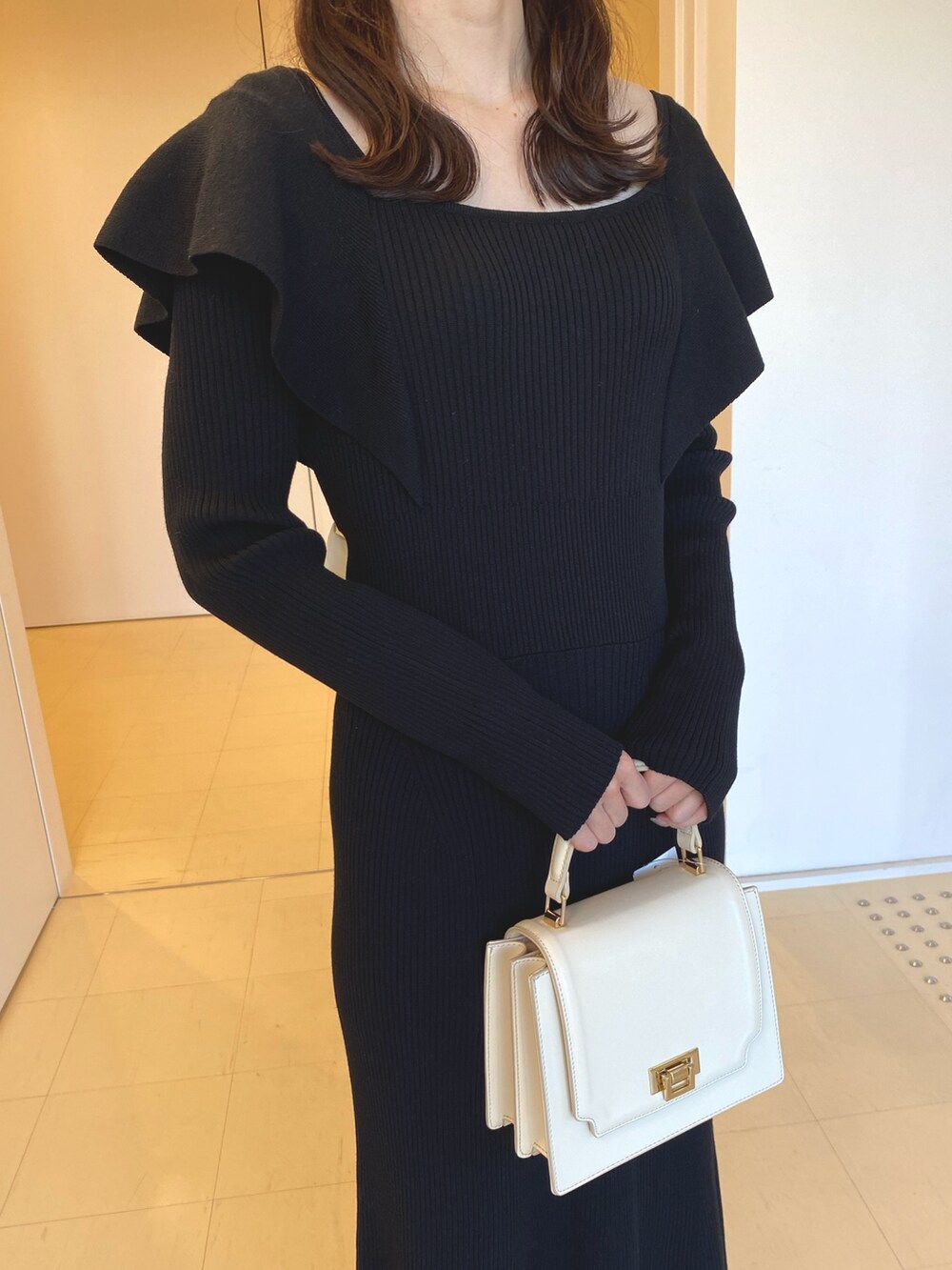 ブラック系のワンピース、ホワイト系のハンドバッグ、ブラウン系のブーツを着用したレディースの冬コーディネートの5枚目の写真