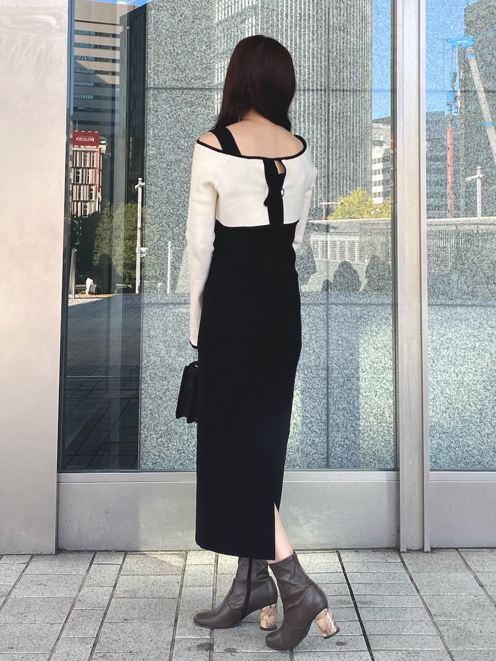 ブラック系のワンピース、ブラック系のショルダーバッグ、ブラウン系のブーツを着用したレディースの冬コーディネートの4枚目の写真